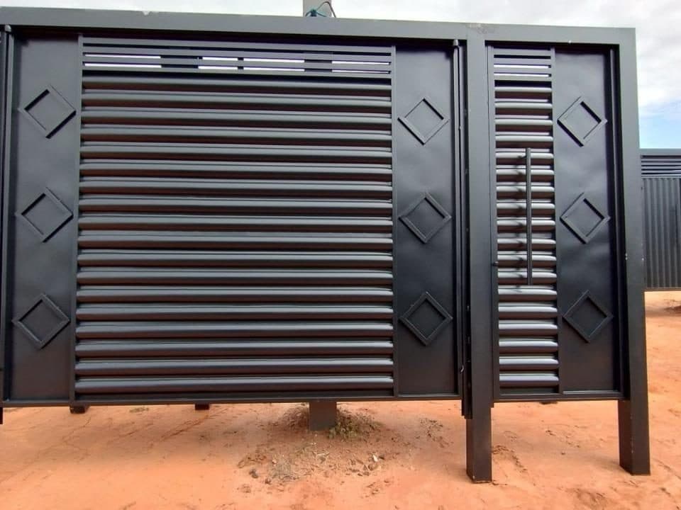Portão de aço preto com ripas horizontais, losangos nas laterais e portão social, pronto no pátio